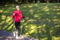 Full Length Portrait of Positive Sportive Senior Woman Doing Nordic Walking in Park. Horizontal image Orientation