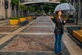 Full length portrait of positive young woman in elegant hat standing on European city street with transparent umbrella Royalty Free Stock Photo