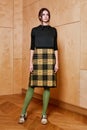 Full length portrait of a pretty brunette girl wearing a black shirt and plaid skirt and in green tights. Standing pose Royalty Free Stock Photo