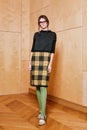 Full length portrait of a pretty brunette girl wearing a black shirt and plaid skirt and in green tights. Standing pose Royalty Free Stock Photo