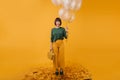 Full-length portrait of pretty woman with purse isolated on yellow background. Indoor shot of stylish birthday girl