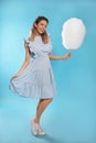 Full length portrait of pretty young woman with tasty cotton candy