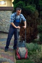 Full length gardener trimming grass lawn using electric cordless mower. Landscaping Industry. Garden maintenance concept Royalty Free Stock Photo