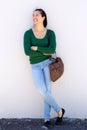 Full length portrait of relaxed asian woman standing outside with arms crossed