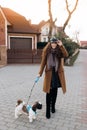 Full-length portrait of romantic young lady in summer hat walking dog. Royalty Free Stock Photo