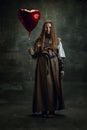 Full-length portrait of sad beautiful woman in image of medieval warrior or knight with dirty wounded face with heart Royalty Free Stock Photo