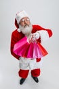 Full-length portrait of senior man wearing Santa Claus costume, holding many shopping packages isolated over white Royalty Free Stock Photo