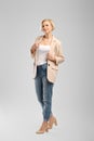 Full length portrait of senior woman in white tank top, beige jacket and boyfriend jeans Royalty Free Stock Photo