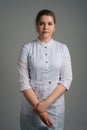 Full length portrait of serious young female doctor wearing medical coat uniform standing on dark isolated background. Royalty Free Stock Photo