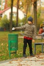 Full length portrait of a six year old boy throwing paper to the trash bin / garbage can in the park Royalty Free Stock Photo