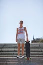 Full-length portrait of a skateboarder. Teen with a skateboard on a sky background. Skateboarding concept. Copy space. Royalty Free Stock Photo