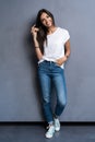 Full length portrait of a smiling casual woman standing on gray background. Looking at camera. Royalty Free Stock Photo