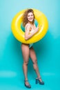 Full length portrait of a smiling girl dressed in swimsuit posing with inflatable ring isolated over blue background Royalty Free Stock Photo