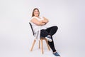 Full length portrait of smiling plus size woman in casual white and black business suit sitting on black chair over gray Royalty Free Stock Photo