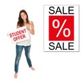 Full length portrait of a smiling student holding a paper in front of a sale poster Royalty Free Stock Photo