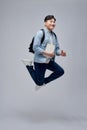 Full length portrait of a smiling young man dressed carrying backpack isolated, holding books, jumping Royalty Free Stock Photo