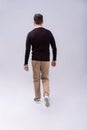 Full length portrait of a smiling young man walking isolated over gray background. Royalty Free Stock Photo