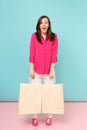 Full length portrait smiling young woman in rose shirt blouse, white pants hold shopping bags isolated on bright pink Royalty Free Stock Photo