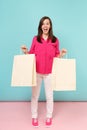 Full length portrait smiling young woman in rose shirt blouse, white pants hold shopping bags isolated on bright pink Royalty Free Stock Photo