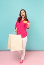 Full length portrait smiling young woman in rose shirt blouse, white pants hold shopping bags isolated on bright pink Royalty Free Stock Photo