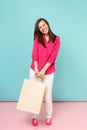 Full length portrait smiling young woman in rose shirt blouse, white pants hold shopping bags isolated on bright pink Royalty Free Stock Photo