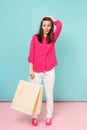 Full length portrait smiling young woman in rose shirt blouse, white pants hold shopping bags isolated on bright pink Royalty Free Stock Photo