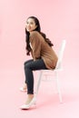 Full length portrait of a smiling young woman sitting on chair Royalty Free Stock Photo