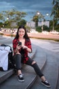 Portrait of smiling young woman sitting on stairs in the city and using smart phone. Royalty Free Stock Photo