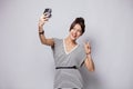 Full length portrait of a smiling young woman taking selfie with camera isolated over white background. Royalty Free Stock Photo