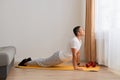 Full length portrait of sporty man practicing advanced yoga, yoga pose, stretching his body, wearing white t shirt and gray pants Royalty Free Stock Photo