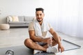 Full length portrait of sporty young Arab man holding bottle of water during his workout at home Royalty Free Stock Photo