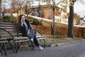 Full-length portrait of student girl sitting on bench in park talking on phone and laughing. Young woman uses smartphone Royalty Free Stock Photo