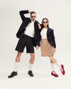 Full-length portrait of stylish young couple, man and woman in retro suit posing  over grey studio background Royalty Free Stock Photo