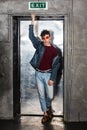 Full length portrait of stylish young fashion model man in bright red sunglasses and denim casual style posing near metallic door Royalty Free Stock Photo