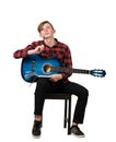 Full length portrait of talented boy teenager with his trendy acoustic guitar seated on chair thinking to compose a new song while