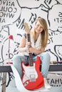 Full-length portrait of teenage girl with electric guitar sitting on study table at home Royalty Free Stock Photo