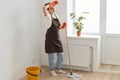 Full length portrait of tired woman housewife wearing orange rubber gloves, brown apron and jeans washing floor at home, being Royalty Free Stock Photo