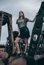 Full length portrait of trendy fashion girl standing on a rusty pile of metal