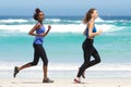 Full length portrait of two fit young women running on beach Royalty Free Stock Photo