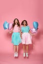 Full length portrait of two happy girls with balloons holding ha Royalty Free Stock Photo