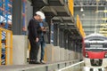 Full length portrait of two male supervisor using a digital tablet to discuss maintenance of the electric skytrain system.