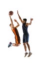 Full-length portrait of two young men, professional basketball players in a jump, throwing ball into basket isolated Royalty Free Stock Photo