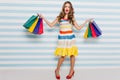 Full-length portrait of well-dressed shopaholic girl holding purchases. Indoor photo of dreamy female model wears red