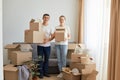 Full length portrait of woman and man, young couple wearing white t shirts standing with cardboard boxes, relocating to a new Royalty Free Stock Photo
