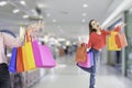 Full length portrait woman standing carry shopping bag in hand, fun and happy,background in mall,with concept of shopping and Royalty Free Stock Photo