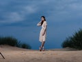 full-length portrait of a woman in a sundress and red sandals on the sand on the beach Royalty Free Stock Photo
