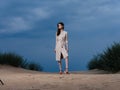 full-length portrait of a woman in a sundress and red sandals on the sand on the beach Royalty Free Stock Photo