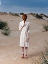 full-length portrait of a woman in a sundress and red sandals on the sand on the beach Royalty Free Stock Photo