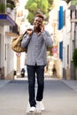 Full length young african male traveler walking outdoors and talking cell phone Royalty Free Stock Photo