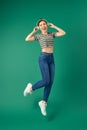 Full length portrait of young Asian woman in headphones listening to music dancing isolated green background Royalty Free Stock Photo
